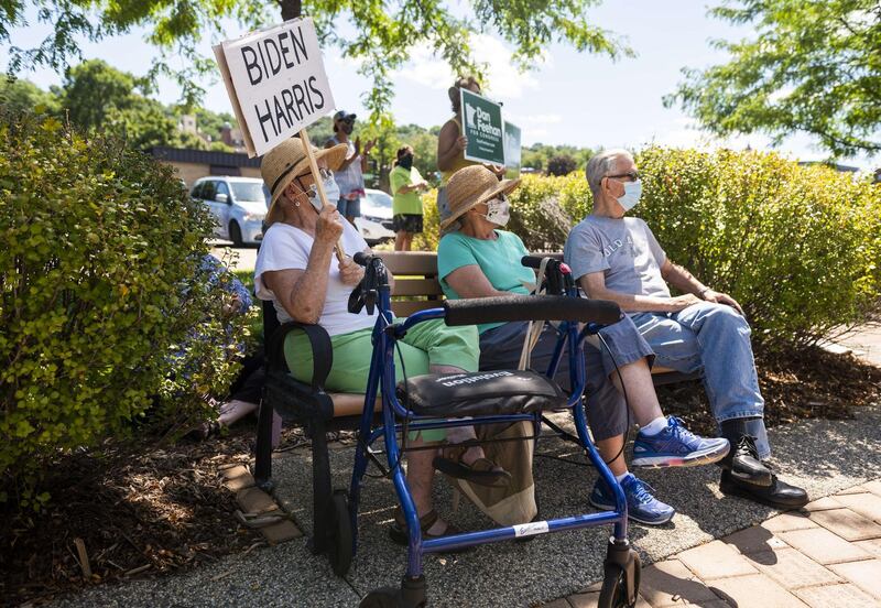 A woman holds a sign that reads 'Biden Harris' as protesters gather near another President Donald Trump campaign stop, this time in Minnesota.AFP