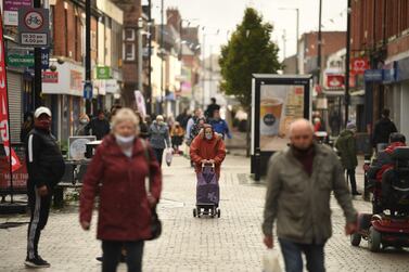 Shoppers wearing mask in the high street in Greater Manchester, northwest England. Tightening government restrictions coupled with falling consumer sentiment may hurt retail sales going forward. AFP