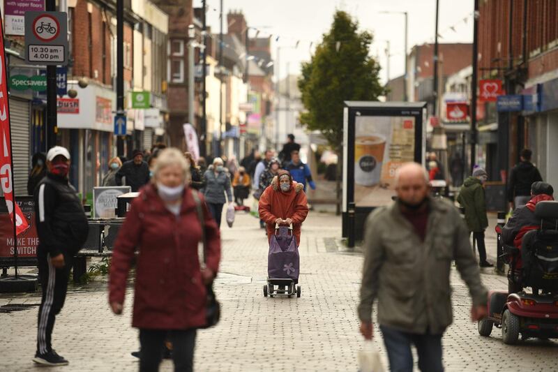 People wearing masks because the novel coronavirus pandemic walk in the high street in Leigh, Greater Manchester, northwest England on October 22, 2020 ahead of new coronavirus restrictions coming into force in the area.  British Prime Minister Boris Johnson imposed tougher coronavirus restrictions on an area of the northewest of England after placing Greater Manchester into the government's tier 3, the highest coronavirus alert level, defying local leaders who bitterly opposed the move without extra funding. The extra restrictions which servely limits social mixing in hospitality venues will come into effect on October 23, 2020.  / AFP / Oli SCARFF
