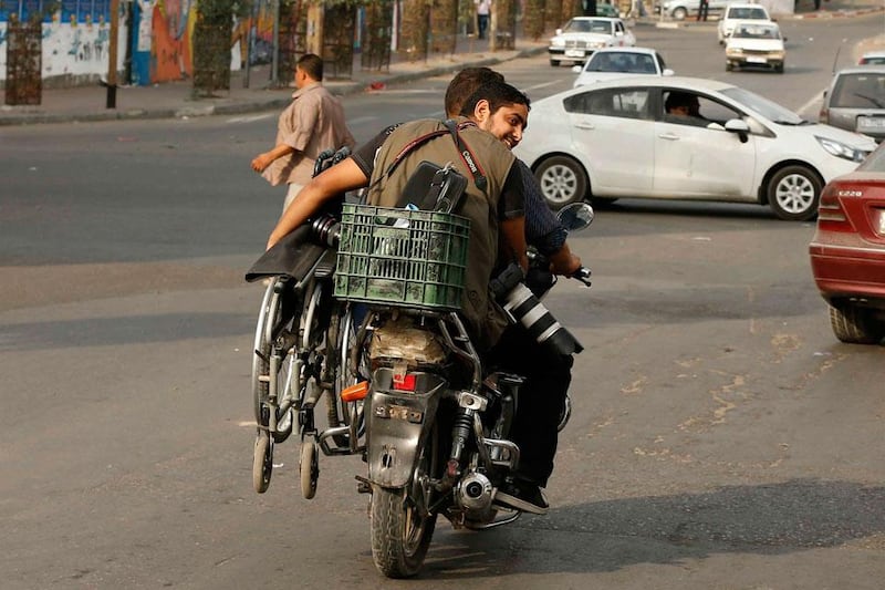 Moamen Qreiqea holds his wheelchair as he rides on a motorcycle.