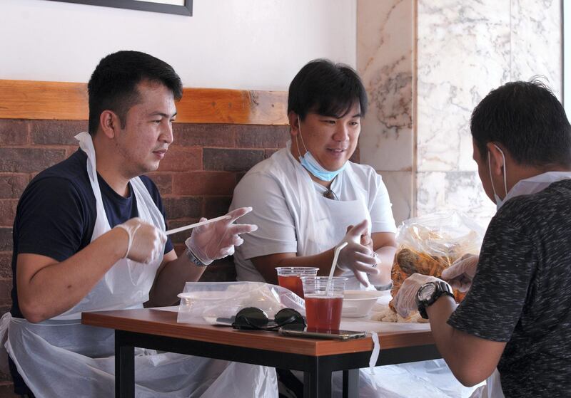 Abu Dhabi, United Arab Emirates, July 4, 2020.   
  Customers at Off The Hook Seafood Restaurant put on their disposable gloves before having their lunch at the Tourist Club Area, Abu Dhabi.
Victor Besa  / The National
Section:  NA 
Reporter: