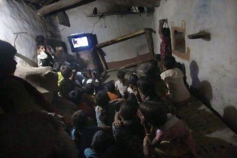 Children watch television powered by solar energy in central India’s Meerwada village. The arrival of solar power last year has changed their lives.