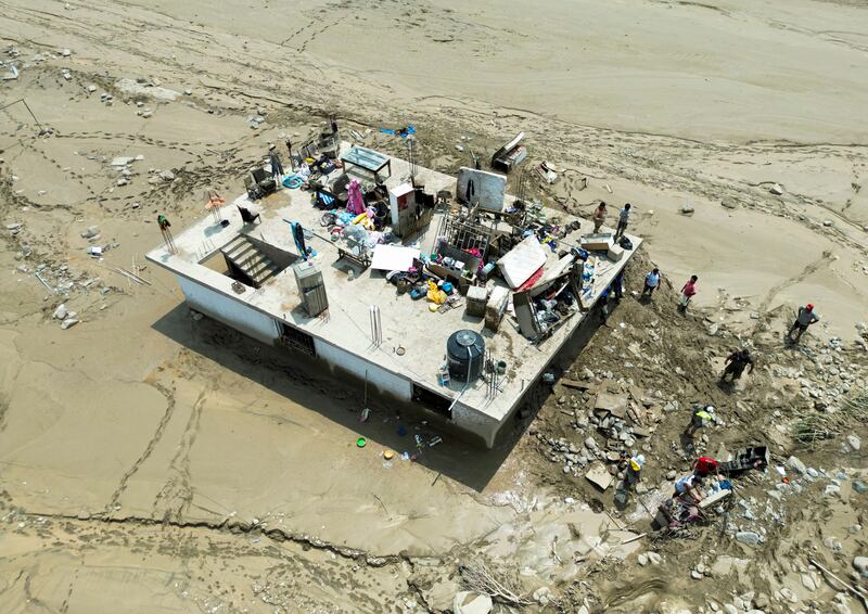 People guard their belongings on top of a building after a landslide triggered by Cyclone Yaku in Peru. Reuters

