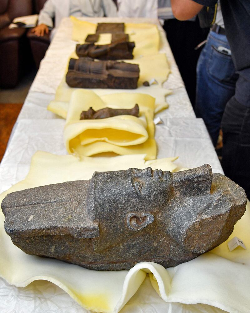 This picture taken on June 16, 2022 in Kuwait City shows a view of a fragment showing the head of a statue of the ancient Egyptian god Amun (Bottom) and other artefacts smuggled from Egypt to Kuwait and returned in a handover ceremony attended by officials from Kuwait's National Council for Culture, Arts, and Literature (NCCAL) at the Egyptian embassy in Kuwait City.  (Photo by YASSER AL-ZAYYAT  /  AFP)