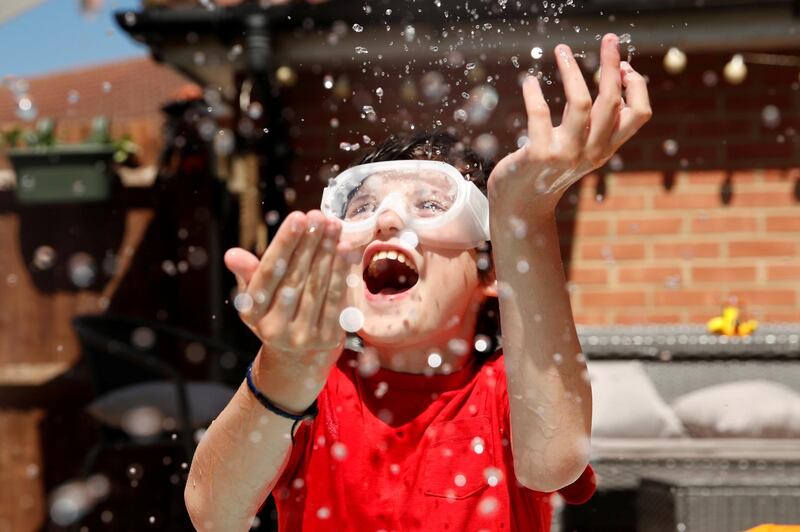 Noah, 10, cools himself off in his garden during hot weather in Hertford, Britain. REUTERS