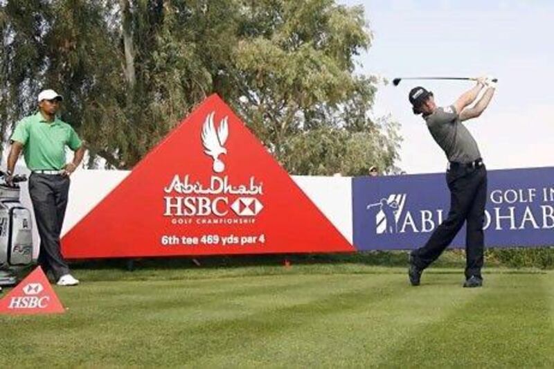 Tiger Woods, left, watches Rory McIlroy tee off on the sixth hole during the first round of the Abu Dhabi HSBC Golf Championship. Jeff Topping / The National