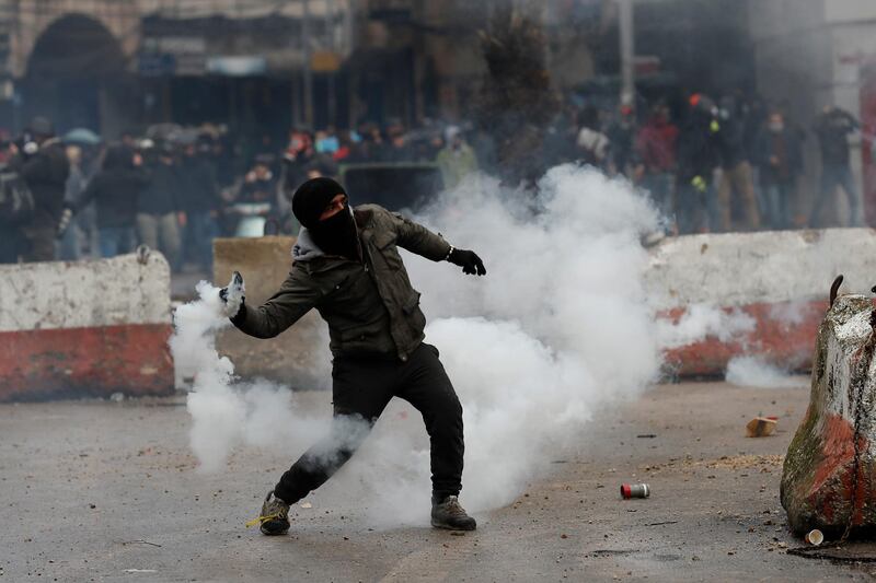 A protester throws back a tear gas canisters towards riot policemen in Tripoli. AP