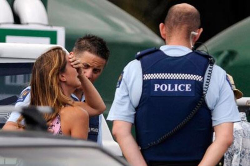 Police comfort a woman believed to be a family member of a man attacked by a shark at Muriwai Beach. Ross Land / AP Photo