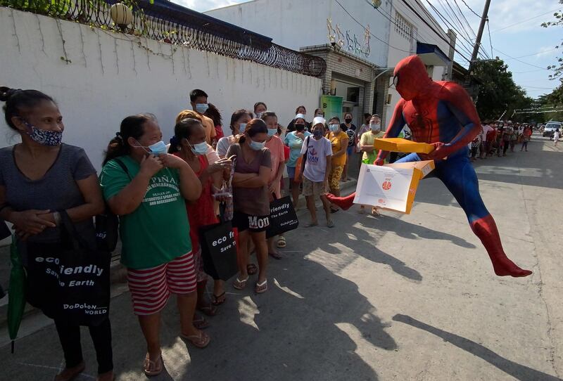 Paolo Felizarta, wearing a Spiderman costume, distributes free food items to citizens affected by Covid-19 quarantine measures along a street in Las Pinas, south of Manila, Philippines. EPA