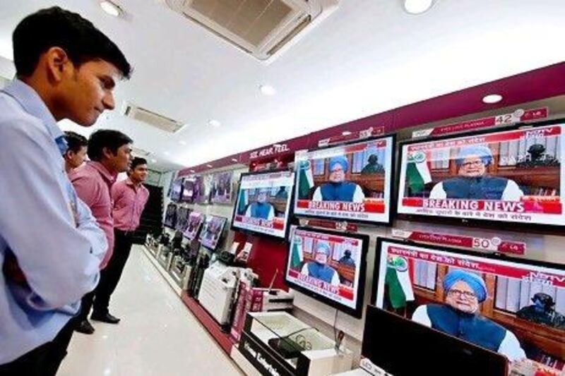 Salesmen watch television screens with images of Indian prime minister Manmohan Singh as he addresses the nation in New Delhi on September 21.