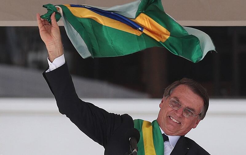 epaselect epa07257476 Brazilian newly inaugurated President Jair Bolsonaro waves the national flag as he delivers a speech after receiving the presidential band during his inauguration ceremony at the Planalto Palace in Brasilia, Brazil, 01 January 2019. A far-right president leads the biggest Latin America democracy for first time since the end of military rule (1964-1985). Bolsonaro defeated candidate Fernando Haddad in the runoff, held last October, receiving 55 percent of the vote.  EPA/MARCELO SAYAO