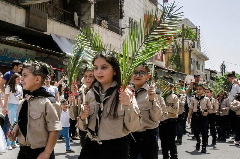 Boy and girl scouts march with palm fronds during the procession in Dwelaa. AFP