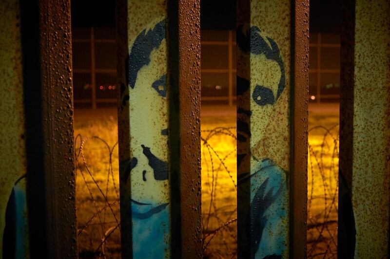 An image of a boy is painted on the bars of the border wall, in front of coils of razor wire seen from Tijuana, Mexico. The partial government shutdown was on track to become the longest closure in US history as President Donald Trump and nervous Republicans looked for a way out of the mess. A solution couldn't come soon enough for federal workers who got pay statements Friday but no pay.  AP
