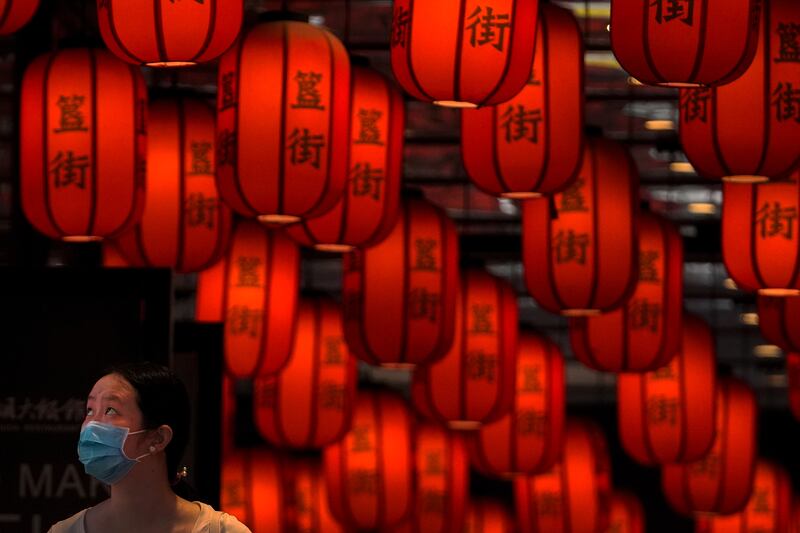 A woman wearing a face mask looks as she walks through red lanterns on display at a subway station in Beijing, Sunday, June 26, 2022.  (AP Photo / Andy Wong)