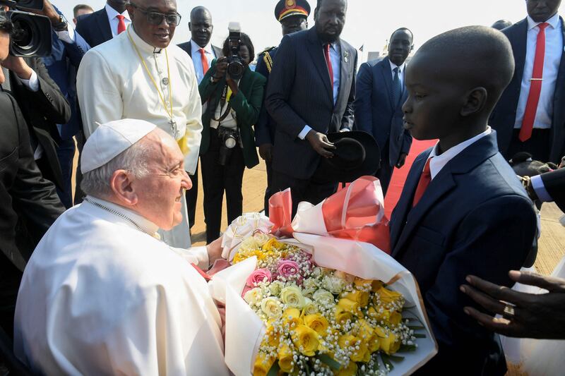 Pope Francis receives a bouquet of flowers from a child. AFP