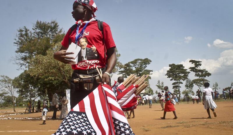A vendor in Kenya selling flags, caps and t-shirts, and wearing a t-shirt showing President Barack Obama with words in Luo reading "Father has reached home". AP Photo