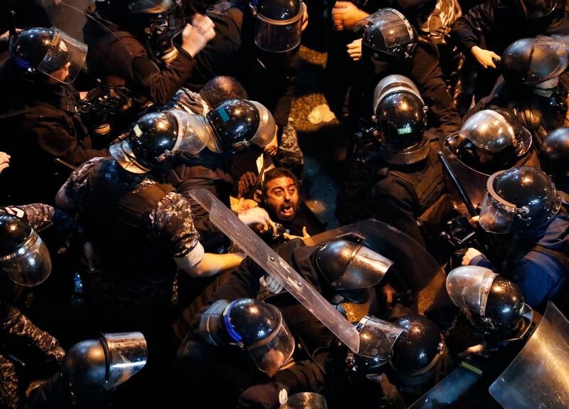 Riot police arrest an anti-government protester who was protesting outside a police headquarters demanding the release of those taken into custody the night before, outside a police headquarter, in Beirut, Lebanon, Wednesday, Jan. 15, 2020. Lebanese security forces arrested 59 people, the police said Wednesday, following clashes overnight outside the central bank as angry protesters vented their fury against the country's ruling elite and the worsening financial crisis. (AP Photo/Hussein Malla)