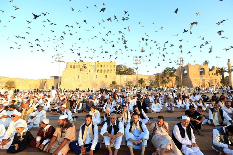 Libyan Muslims sit in Martyrs' Square in the capital Tripoli on September 1, 2017 prior to praying as Muslims across the world celebrate the annual festival of Eid al-Adha, or the festival of sacrifice, which marks the end of the Hajj pilgrimage to Mecca and commemorates prophet Abraham's readiness to sacrifice his son to show obedience to God. / AFP PHOTO / MAHMUD TURKIA