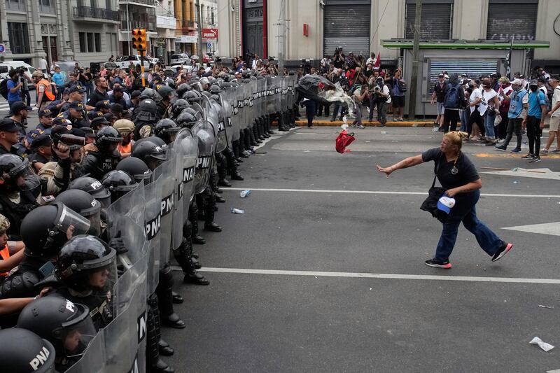 A woman throws a bag of rubbish at police blocking an anti-government demonstration against food scarcity and economic reforms proposed by Argentinian President Javier Milei, in Buenos Aires. AP
