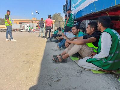 Egyptian volunteers sit on the ground next to trucks at the Rafah crossing into Gaza as aid groups wait for it to be re-opened. Reuters