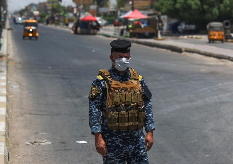 A member of the Iraqi security forces stands guard at a checkpoint, enforcing a curfew due to the COVID-19 coronavirus pandemic, in Baghdad's eastern Sadr City suburb on May 31, 2020. The Iraqi authorities imposed a week-long curfew to curb the latest increase in infections of coronavirus in the country. / AFP / AHMAD AL-RUBAYE
