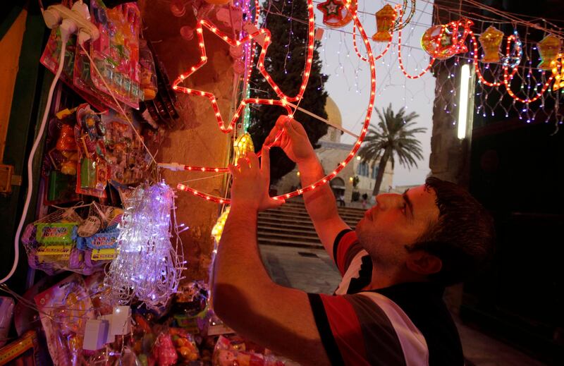 A Palestinian vendor hangs decorations for the upcoming holy month of Ramadan at a market in Jerusalem's Old City July 31, 2011. Muslims around the world abstain from eating, drinking and conducting sexual relations from sunrise to sunset during Ramadan, the holiest month in the Islamic calendar.  The Dome of the Rock on the compound known to Muslims as al-Haram al-Sharif, and to Jews as Temple Mount, is seen in the back.  REUTERS/Ammar Awad (JERUSALEM - Tags: RELIGION SOCIETY) *** Local Caption ***  JER10_PALESTINIANS-_0731_11.JPG
