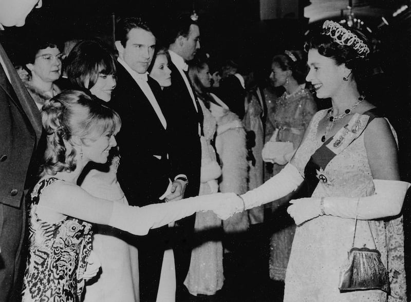 British actress Julie Christie curtsies to Queen Elizabeth II, in 1965. Getty Images