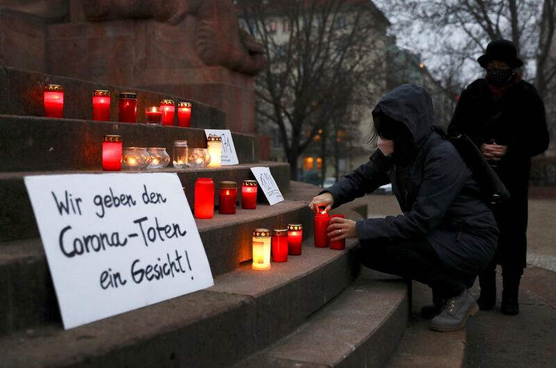 A person wearing protective mask lights a candle on a vigil organised by activist-group #wirgebendenToteneinGesicht (We give a face to the dead) to commemorate the people who died due to the coronavirus disease (COVID-19) in Berlin, Germany, December 13, 2020. REUTERS/Christian Mang