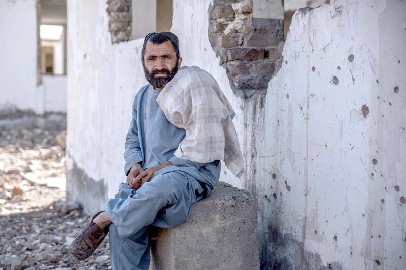 A man sits outside the former office of the governor of Nawa-i-Barakzai district that has been bombed and attacked by the Taliban, leaving ruins and bullet-riddled walls. Photo by Stefanie Glinski