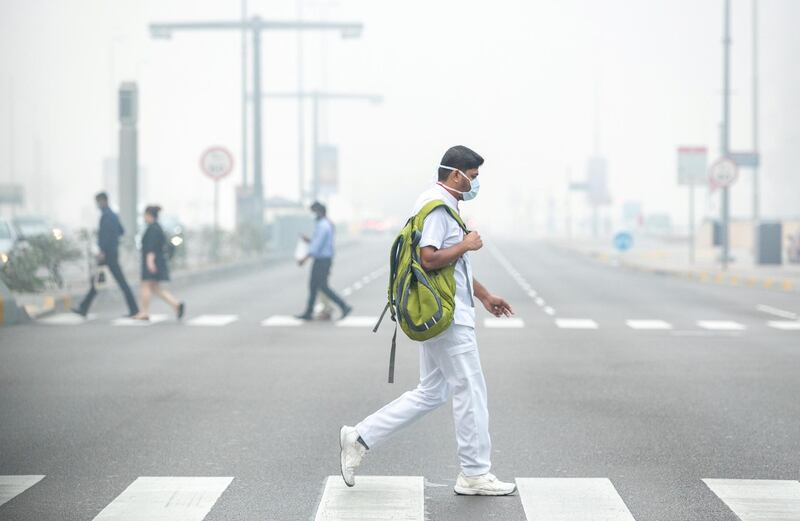 Abu Dhabi, United Arab Emirates, February 16, 2021.  A healthcare worker crosses the street during foggy weather at central Abu Dhabi on a Tuesday morning.
Victor Besa/The National
Section:  NA/Weather/Big Picture