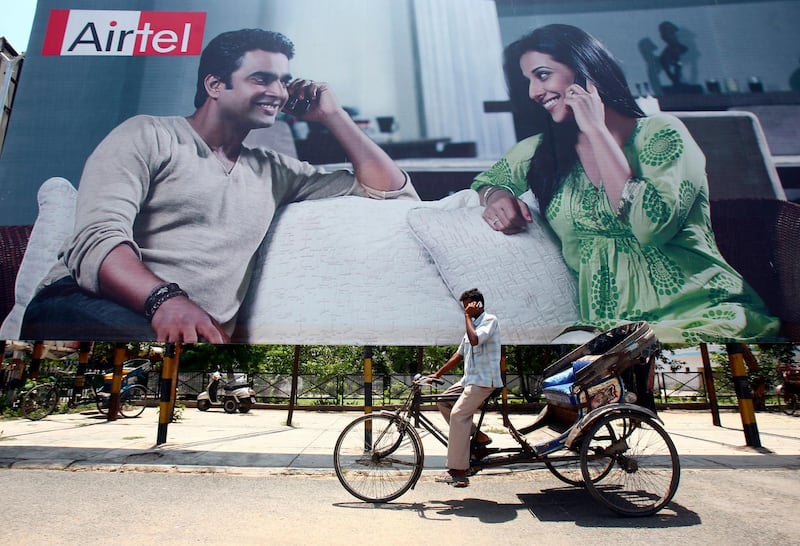 A rickshaw driver talks on his mobile phone as he rides past a billboard outside a railway station in the northern Indian city of Chandigarh May 26, 2009. India's Bharti Airtel, which has restarted merger talks with South Africa's MTN Group, said on Tuesday it does not expect funding requirements for the deal to be onerous.  The talks could lead to a merger creating one of the world's biggest cell phone groups by subscribers through the combination of India's biggest operator and MTN, which runs networks across 21 markets in Africa and the Middle East. REUTERS/Ajay Verma (INDIA BUSINESS) - GM1E55Q1AAM02