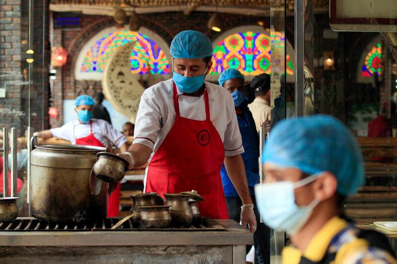 A restaurant worker, wearing a protective face mask, waits for clients at a restaurant in the Yemeni capital Sanaa. AFP