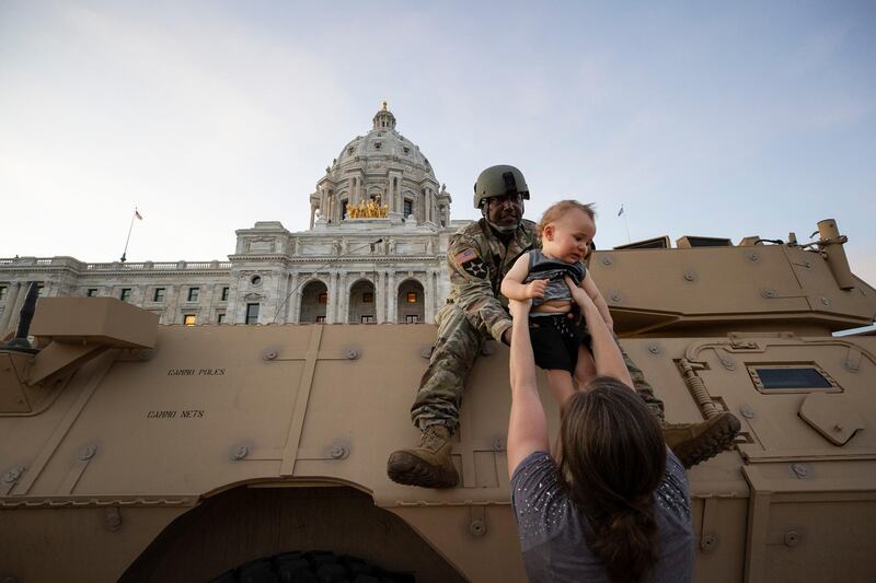 Natasha Robinson passes her one-year-old son Azrael Hammick up to Master Sgt Acie Matthews Jr. during a protest at the at the Minnesota state Capitol in St Paul, during protests over the death of George Floyd, who died May 25 after being restrained by Minneapolis police. AP