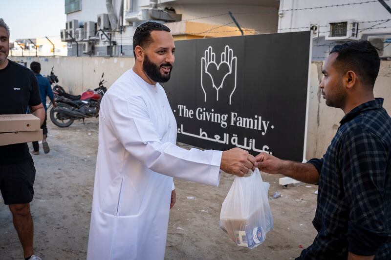 Fadie Musallet, who runs The Giving Family, hands out an iftar meal. Antonie Robertson / The National