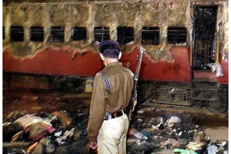 A policeman stands near the burnt-out train carriage in which 59 passengers died in 2002. Yesterday, a court convicted 31 Muslims who were charged with setting the fire.
