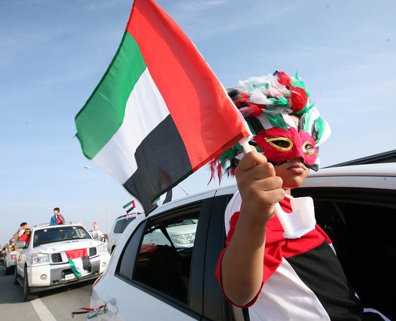 A child waves a UAE flag during the car parade in celebration of the 38th anniversary of Federation in Umm Al Quwain. Paulo Vecina / The National