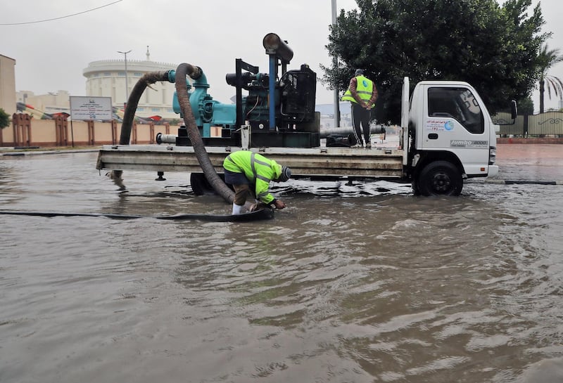 Municipal workers try to clear flood water from a street during a heavy rain shower in Cairo. EPA