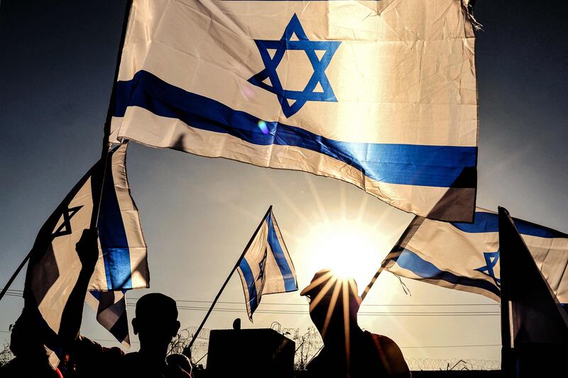 Israeli military veterans wave national flags during a rally against the government's judicial reform bill, near Netanya. AFP