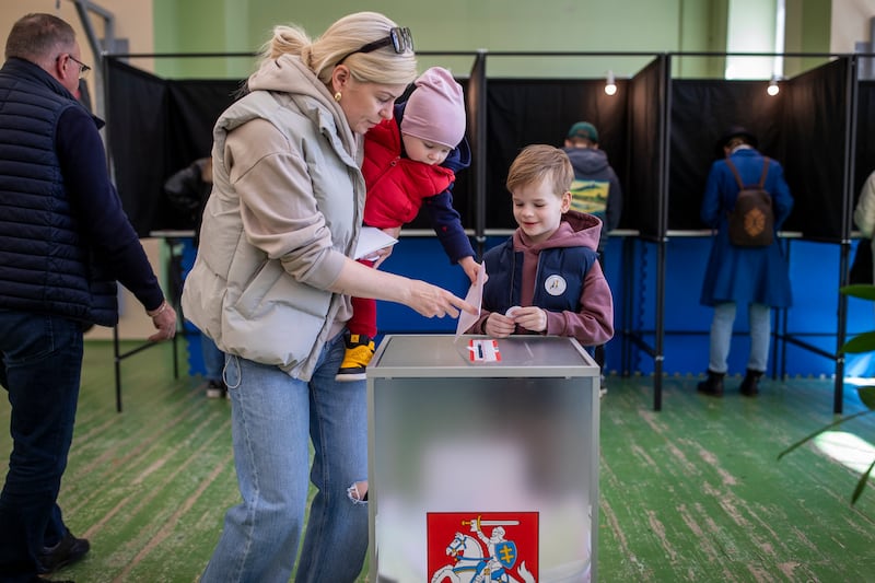 A woman with children casts her ballot in Vilnius, Lithuania. Polls closed at 8pm local time, with results expected after midnight. AP