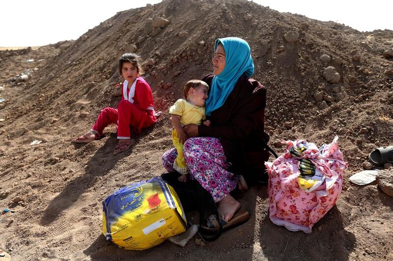 An Iraqi woman who fled her village holds her daughter near a Kurdish checkpoint, in the Khazer area between the Iraqi city of Mosul and the Kurdish city of Erbil, on June 26, 2014. Hundreds of villagers fleeing advances by Sunni militants sought shelter in Iraqi Kurdish-controlled territory. Hussein Malla / AP Photo