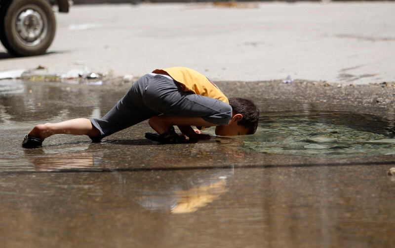 A boy drinks water from a burst water pipe in Aleppo's Karm al-Jabal district, June 2, 2013. REUTERS/Muzaffar Salman (SYRIA - Tags: CIVIL UNREST TPX IMAGES OF THE DAY) *** Local Caption ***  SYR19_SYRIA-CRISIS-_0602_11.JPG