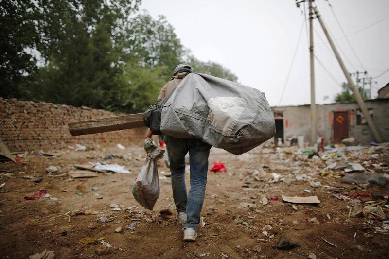 A garbage collector carries a sack of items abandoned by recycling workers at Dongxiaokou village. Kim Kyung-Hoon / Reuters