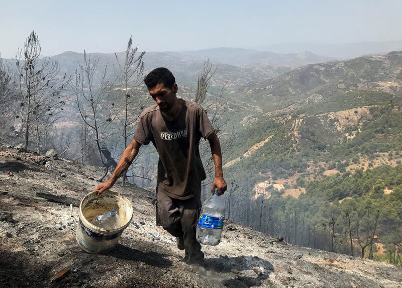 A man carries water containers as he helps to douse hotspots in an area hit by a wildfire in El Bir village, Bejaia province, Algeria.