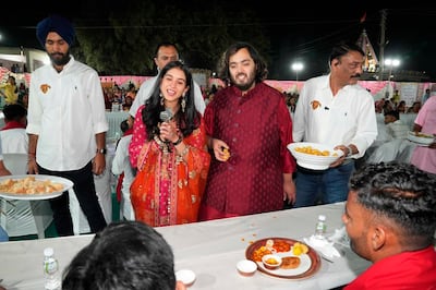 This photograph released by the Reliance group shows Reliance Industries Chairman Mukesh Ambani's son and groom Anant Ambani, center right, and bride Radhika Merchant, center left interacting with guests during a community food service held as part of their pre-wedding celebrations at Jogvad village near Jamnagar, India, Wednesday, Feb. 28, 2024.  (Reliance group via AP)