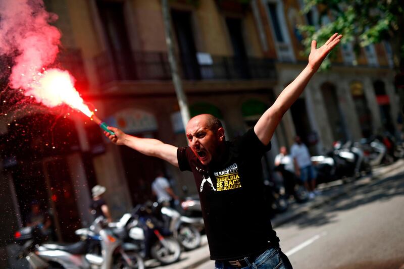 A taxi driver shouts slogans while holding a flare during a strike by cab drivers in Barcelona.  AFP / Pau Barrena