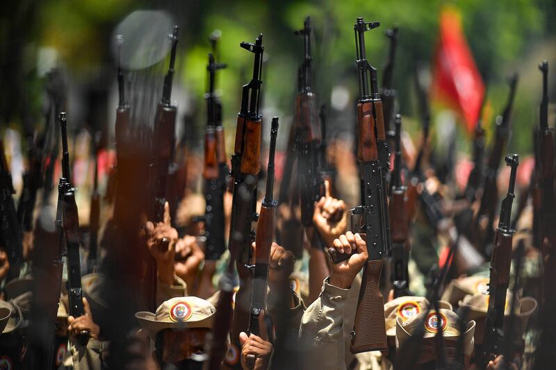 Members of the Venezuelan National Bolivarian Militia, a branch of the National Armed Forces created by the late president Hugo Chavez, celebrate the militia´s 13th anniversary, in Caracas, Venezuela. Government supporters are also commemorating the 20th anniversary of Chavez's return to power after a failed coup in 2002. AP