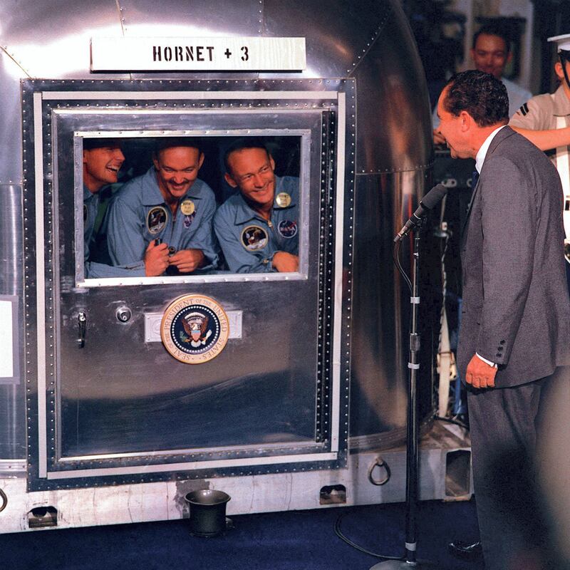 US Apollo 11 astronauts Neil A. Armstrong (L), Michael Collins (C), and Edwin E. Aldrin, Jr.(R), smile at US President Richard Nixon from their quarantine cabin on July 24, 1969 aboard the USS Hornet, after the successful completion of their lunar landing mission. The astronauts were placed in quarantine for almost three weeks after their landing on the moon for fear that the moon might contain undiscovered pathogens. AFP PHOTO NASA (Photo by - / NASA / AFP)