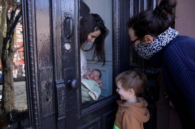 Felix and his mother Naomi Hassebroek look at her sister's newborn baby through a glass door while dropping off a bag of supplies for Easter Sunday in the Brooklyn borough of New York City, US. Reuters