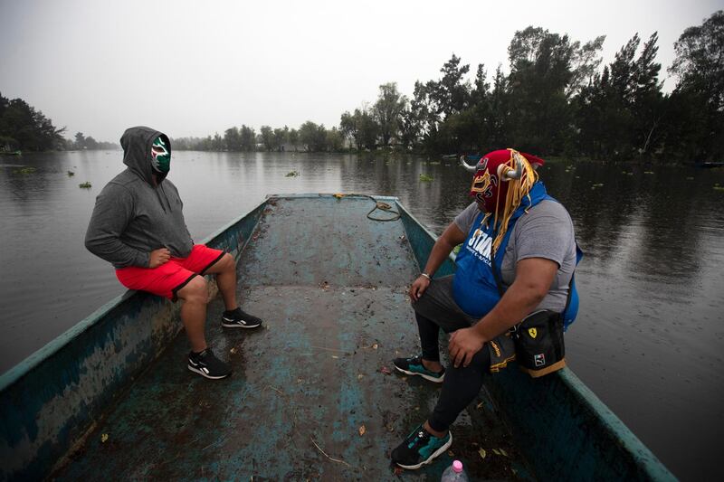 Lucha Libre brothers, "Ciclonico," or Cyclonic, left, and Mister Jerry, ride a boat to their training site on Xochimilco's famous floating gardens on the outskirts of Mexico City. AP Photo