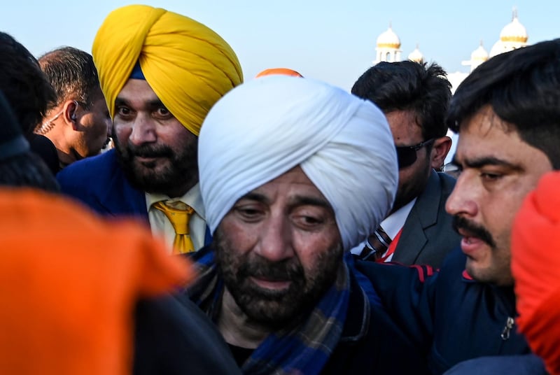 Security personnel escort Indian Bollywood actor Sunny Deol (L) and Indian politician and former cricketer Navjot Singh Sidhu (C) as they visit the Shrine of Baba Guru Nanak Dev at Gurdwara Darbar Sahib in Kartarpur, near the Indian border, on November 9, 2019. Hundreds of Indian Sikhs made a historic pilgrimage to Pakistan on November 9, crossing through a white gate to reach one of their religion's holiest sites, after a landmark deal between the two countries separated by the 1947 partition of the subcontinent. / AFP / AAMIR QURESHI
